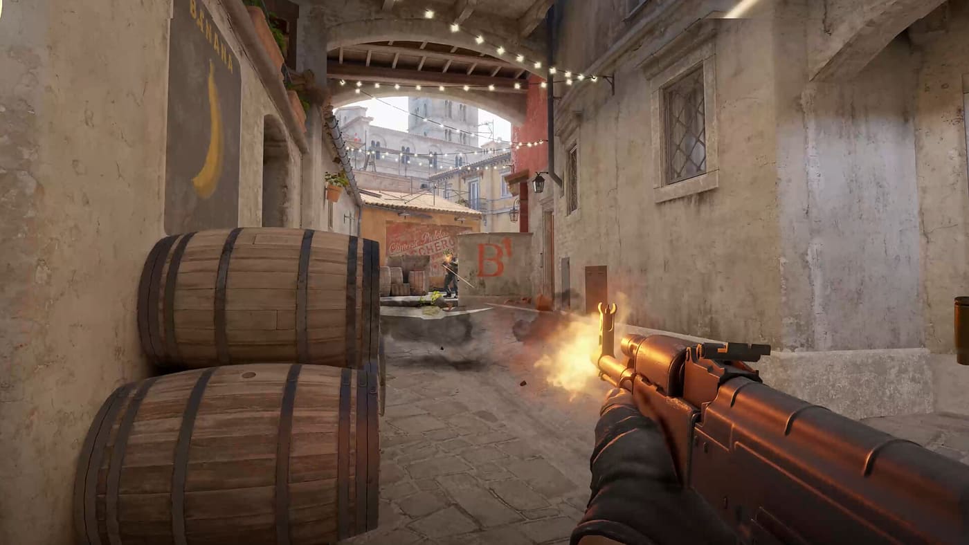 First-person view of a Counter-Strike 2 rifle firing down a narrow street at a distant enemy — official screenshot supplied by Valve